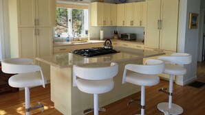 Cozinha moderna com ilha central, banquetas e vista para o exterior.