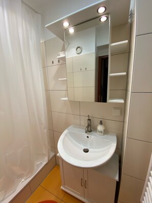 A bathroom with a white sink, mirror, and tiled walls. There is a shower curtain and a towel rack visible. - Comfortable and modern apartment for 4 Personenmit Vollausstattung (Goslar)