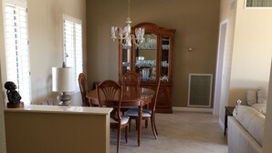 A spacious living area with a dining table, chairs, a chandelier, and a large wooden cabinet. - Newly Renovated Vacation Home With Desert Theme in Premier Golf Community (Sun City West)