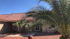 A house with a red-tiled roof, a palm tree, and a cactus in the foreground. - Newly Renovated Vacation Home With Desert Theme in Premier Golf Community (Sun City West)