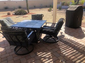 Relax outdoors with a patio table and chairs, surrounded by desert plants and a tree.
