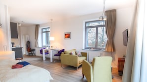 A modern hotel room with a bed, a desk, a sofa, and a chair.