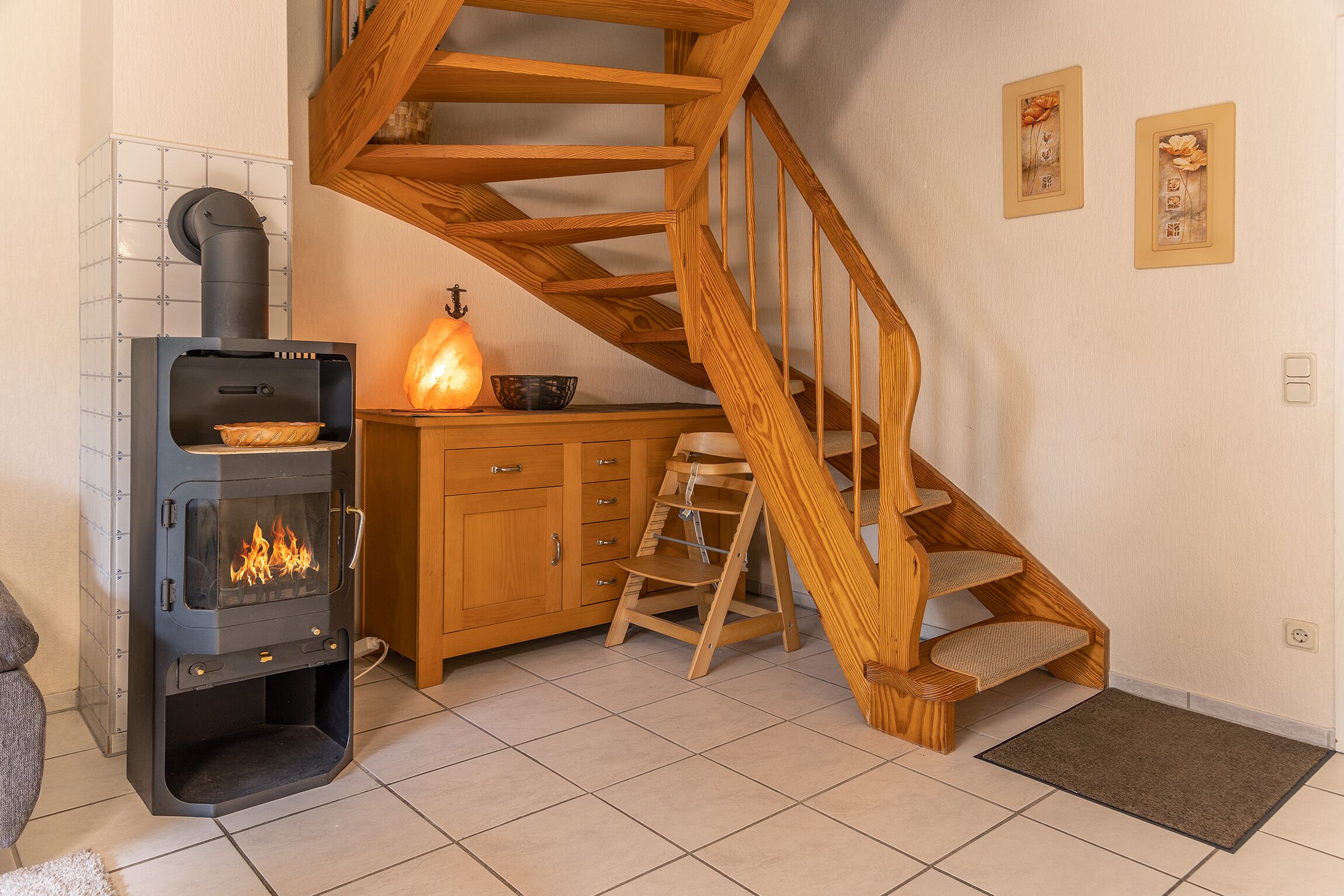 Ein gemütliches Zimmer mit Kaminofen, einer Holztreppe und einem Schrank.