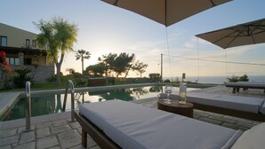 A poolside area with a bed, a bottle of wine, and a lounge chair. - Four-Bedroom Private Family Villa with Pool, 400m from the Beach. Villa Russelia (Kamiros skala)