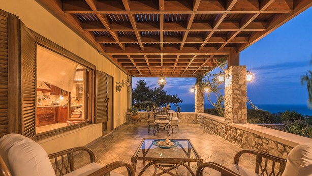 An outdoor patio with a table and chairs, overlooking a scenic view. - Four-Bedroom Private Family Villa with Pool, 400m from the Beach. Villa Russelia (Kamiros skala)