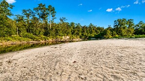A beach with a river, trees, and clear blue sky. - Cozy Cabin on the Creek with 2 private sandbars (Perkinston)