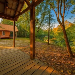 A wooden deck leading to a covered area with a rustic cabin in the background.