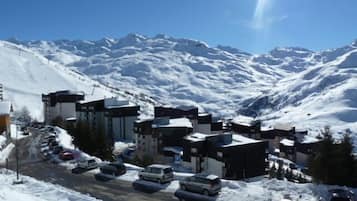 A snow-covered mountain town with modern buildings, a parking lot, and a clear view of the surrounding mountains.