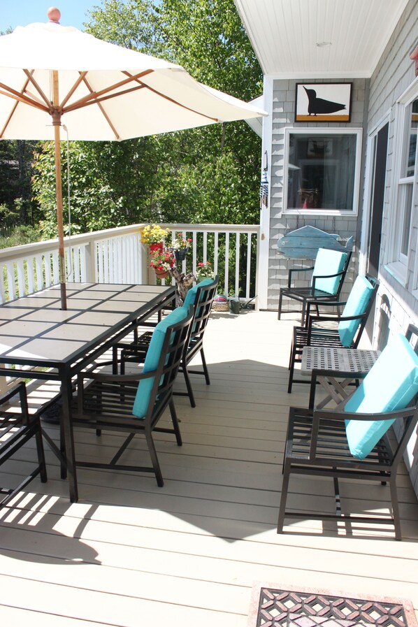 A covered patio with a table and chairs, a large umbrella, and a decorative wall with a bird silhouette.