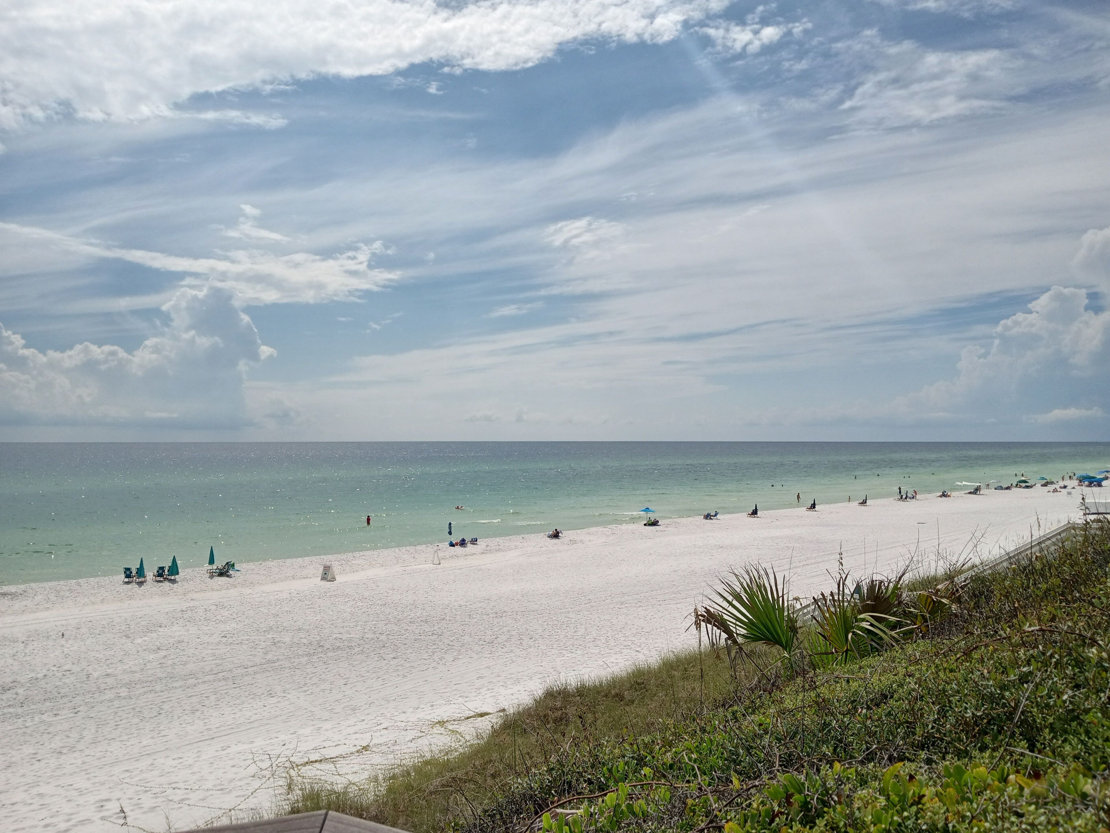 A beach with white sand, clear turquoise water, and a few people.