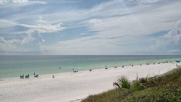 A beach with white sand, clear turquoise water, and a few people.