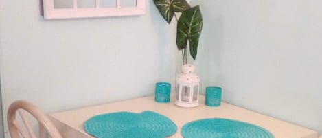 A small dining table with two chairs, a potted plant, and a decorative mirror on the wall.