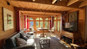 A cozy cabin interior with a leather sofa, a round table, and a television.