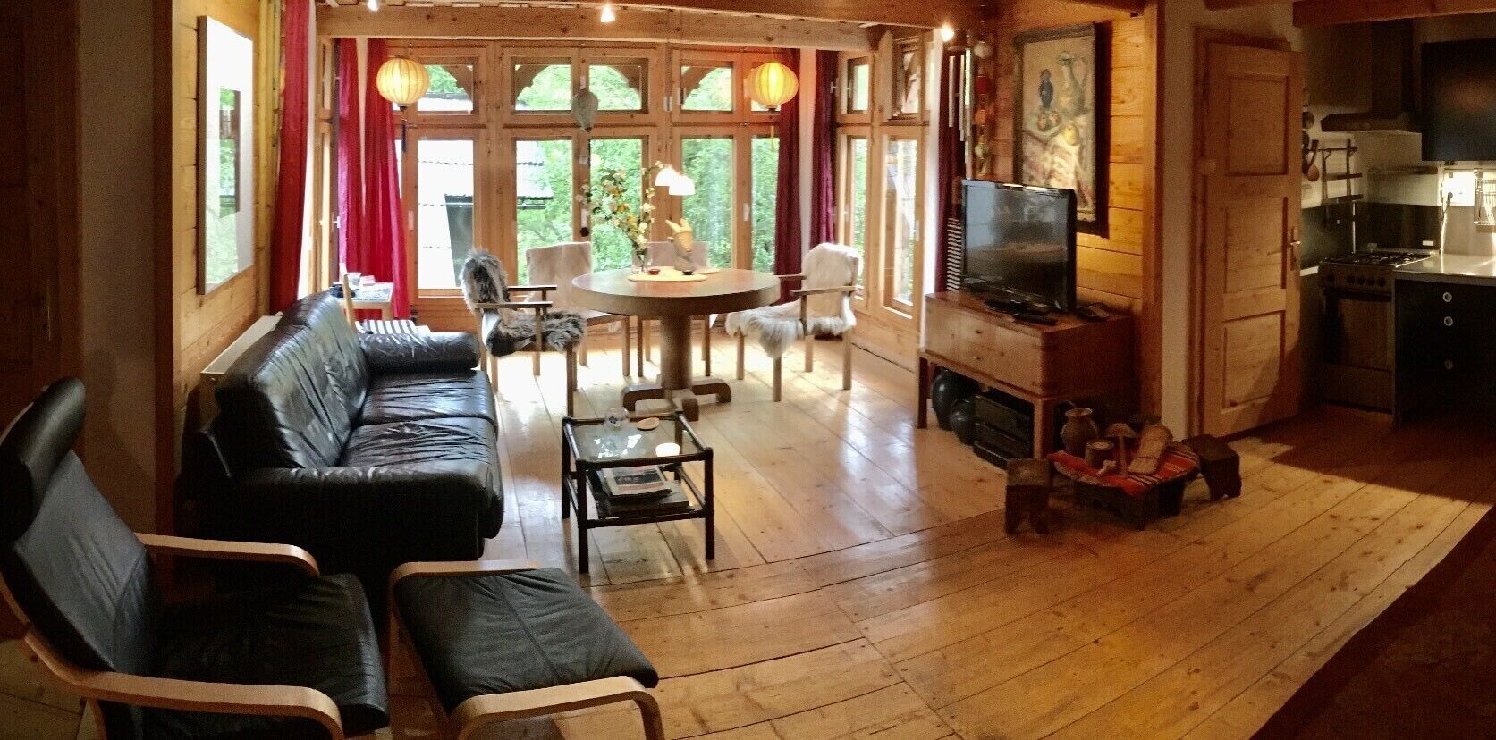 Een gezellige woonkamer met een zwarte leren bank, een eettafel en een open haard.