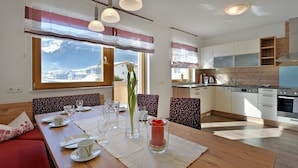A modern kitchen with wooden cabinets, a built-in oven, and a dining area with a wooden table set for four.