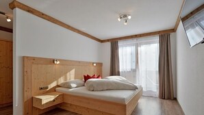 A bedroom with a wooden bed, a nightstand, and a built-in desk.