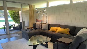 A modern living room with a sectional sofa, a glass coffee table, and a patterned rug.