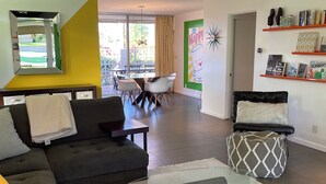 A modern living room with a sofa, a glass coffee table, and a dining area with chairs.