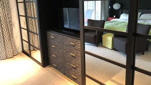 A modern bedroom with a sliding door, a bed with green bedding, a bedside table, and a chair.