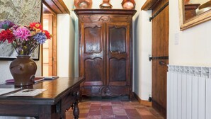 A hallway with a wooden floor, a wooden table with a vase of flowers, and a large wooden door.