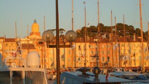 Un port de plaisance où sont amarrés de nombreux voiliers, un bâtiment avec un dôme en arrière-plan et un ciel dégagé.