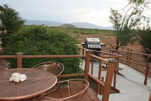 Un patio con mesa y sillas de metal, una parrilla y vistas a montañas.