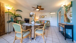 A dining area with a round table, four chairs, and a ceiling fan.