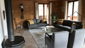 Een gezellige woonkamer met een open haard, twee banken, een salontafel en een eethoek met een stoel en tafel.