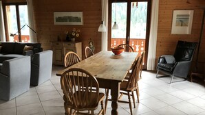 Een gezellig houten interieur met een eettafel, stoelen, een bank en een zwarte lederen fauteuil.