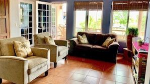 A living room with a brown leather sofa, beige armchairs, and a glass door leading outside. - Villa Sunset, Ocean View rooftop, just 3 blocks from the beach (San Pancho)