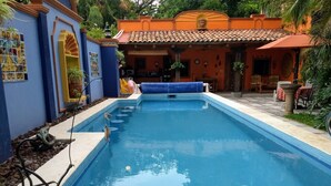 A swimming pool with a tiled deck, surrounded by a building with a tiled roof and a mural. - Casa de Como Casita #2 - Ajijic Village (Ajijic)