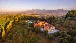 A villa with a swimming pool, surrounded by lush greenery and vineyards, with a view of distant mountains and a valley. - Tenuta Bellosguardo on the hills with Swimming pool and Jacuzi! EXCLUSIVE ESTATE (Lucca)