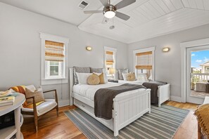 A bedroom with a bed, two bedside tables, a chair, and a window with blinds. - Marshall Cottage - Gulf Views from 3rd Floor Balcony! Free Bikes/Fitness/Tennis (Seacrest Beach)