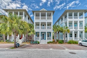 A two-story building with a central balcony, surrounded by palm trees and a paved walkway. - Marshall Cottage - Gulf Views from 3rd Floor Balcony! Free Bikes/Fitness/Tennis (Seacrest Beach)