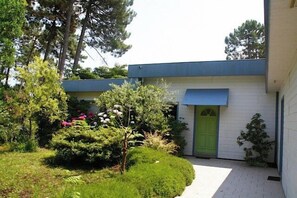 A modern building with a green door, surrounded by well-maintained greenery and a paved pathway. - Lovely house with pool & beautiful garden G0287 (Lacanau)