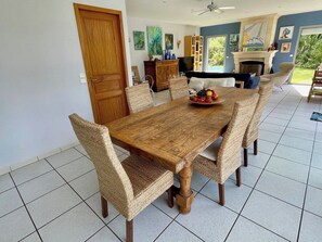 Ein Essbereich mit einem Holztisch, gewebten Stühlen, einem Fernseher und einem Kamin.