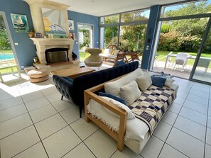 A living room with a fireplace, a sofa, a coffee table, and a view of the outdoors.