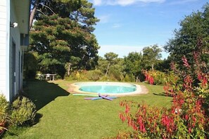 A backyard with a swimming pool, well-maintained lawn, and various plants. - Lovely house with pool & beautiful garden G0287 (Lacanau)