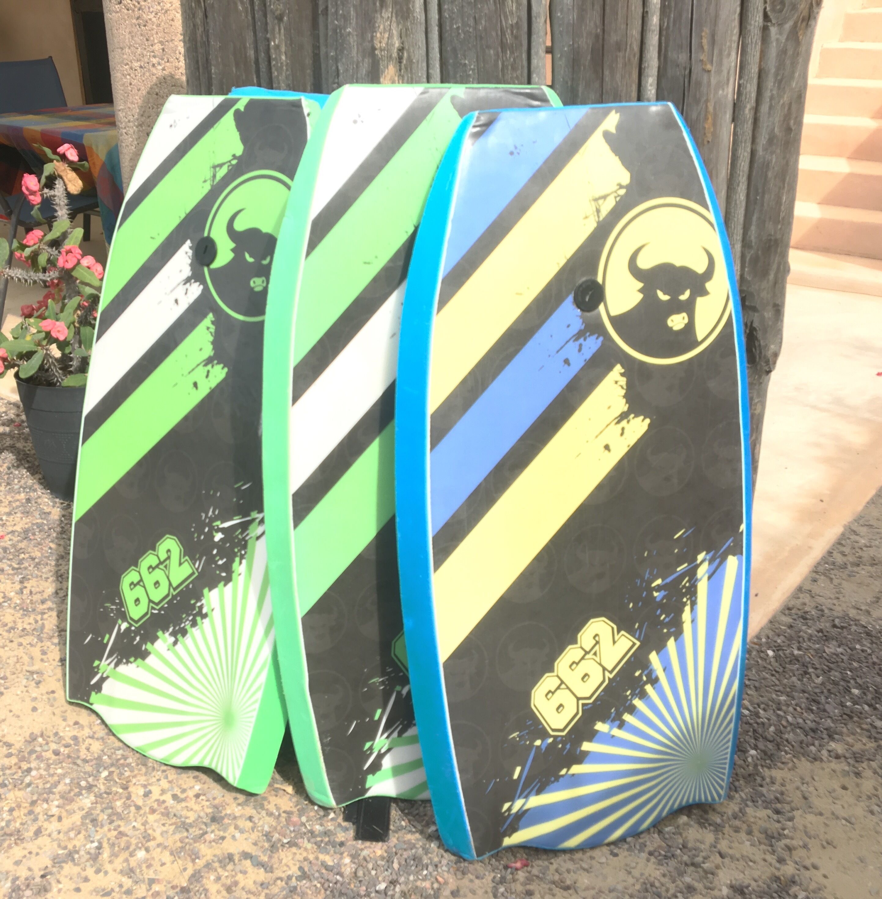 Three surfboards leaning against a wooden structure.
