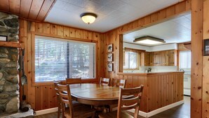 A wooden interior with a stone fireplace, a round dining table, and a kitchen area.