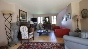 A living room with a fireplace, a red sofa, a blue armchair, and a patterned rug. - 4* listed house with large private garden in a 6-hectare estate (Bangor)