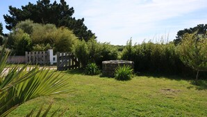A grassy outdoor area with a stone structure, a wooden fence, and dense foliage. - 4* listed house with large private garden in a 6-hectare estate (Bangor)