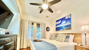 A bedroom with a bed, a ceiling fan, a painting of the ocean, and a desk with a lamp. - Comfy & Quiet Bungalow -Pet Friendly! 30+ Nt min.  Summer 2026 Special! (Houston)