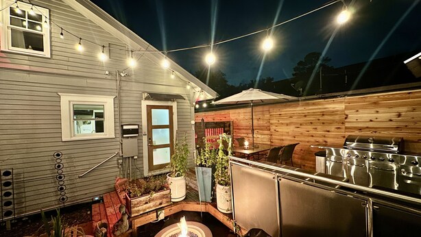 An outdoor patio with a grill, string lights, and a fire pit. - Comfy & Quiet Bungalow -Pet Friendly! 30+ Nt min.  Summer 2026 Special! (Houston)