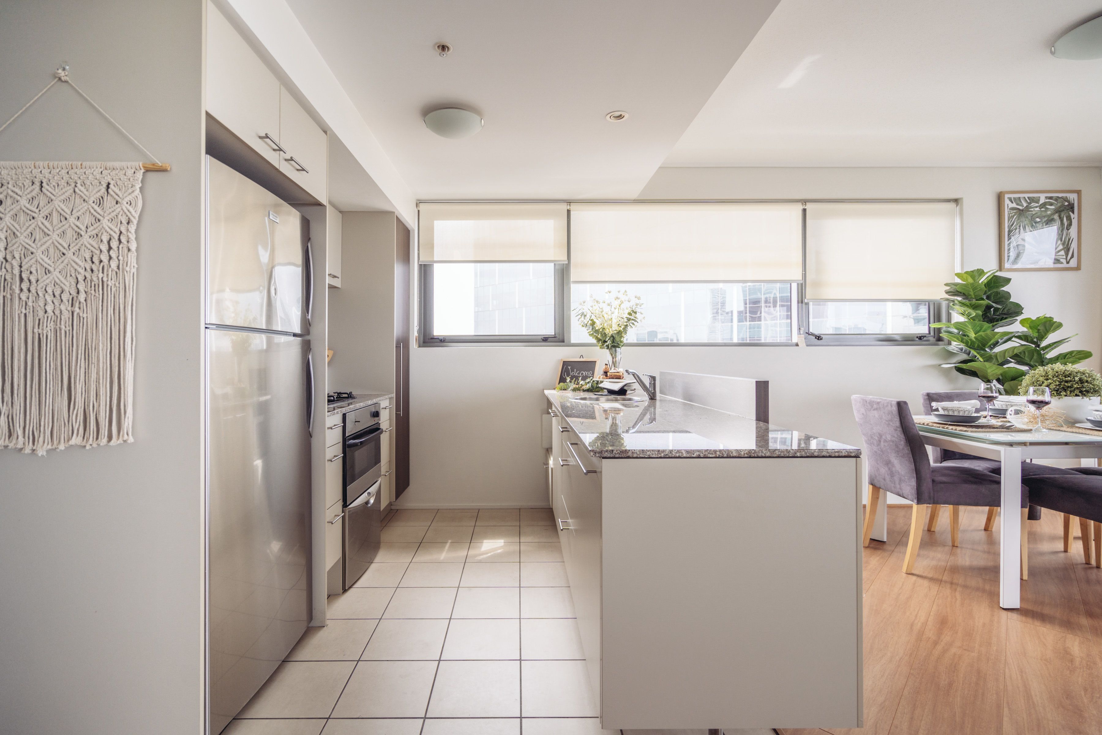 Cocina moderna con refrigerador, horno y pileta integrados. Cuenta con comedor, mesa, sillas y un ventanal que proporciona luz natural.