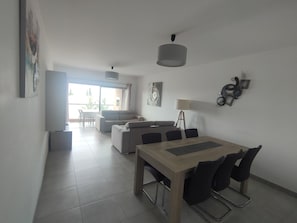 Uma sala de estar moderna com área de jantar, sofá, mesa de centro e luminária.