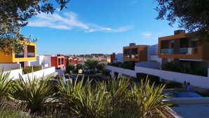 Un quartier résidentiel moderne avec des bâtiments aux couleurs vives, un ciel d’un bleu éclatant et une végétation luxuriante.
