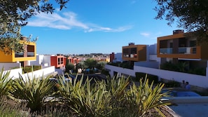 Uma área residencial moderna com edifícios coloridos, céu azul límpido e vegetação exuberante.