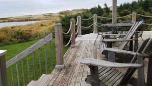 Een houten terras met uitzicht op een meer en glooiende heuvels.