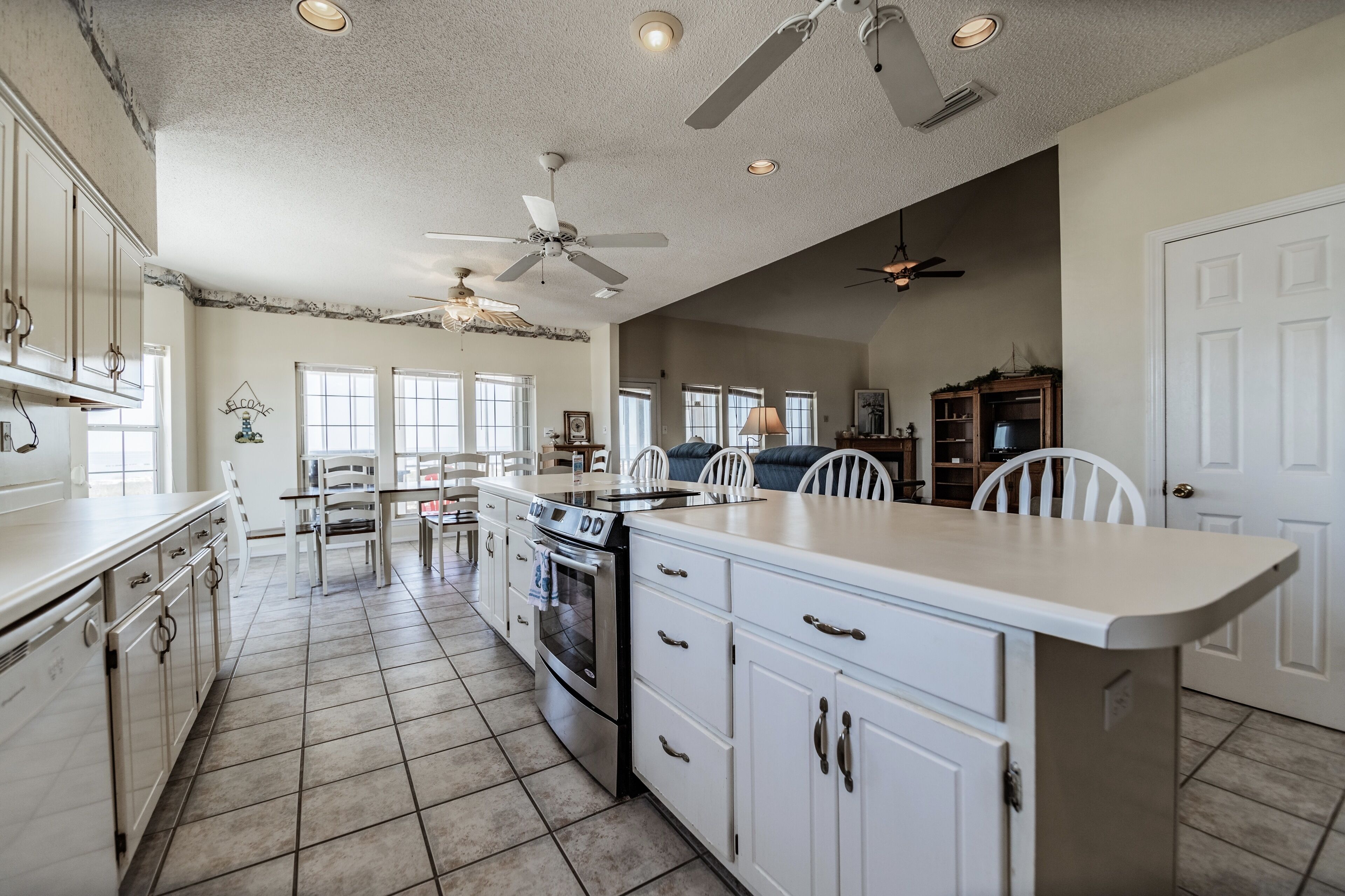 A spacious kitchen with white cabinets, a central island, and a dining area with white chairs.